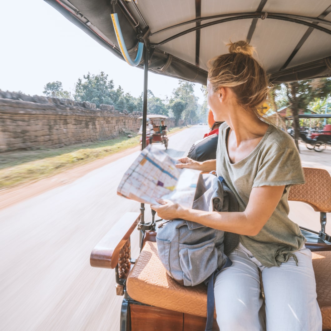 A traveller with a map riding on the back of a rickshaw