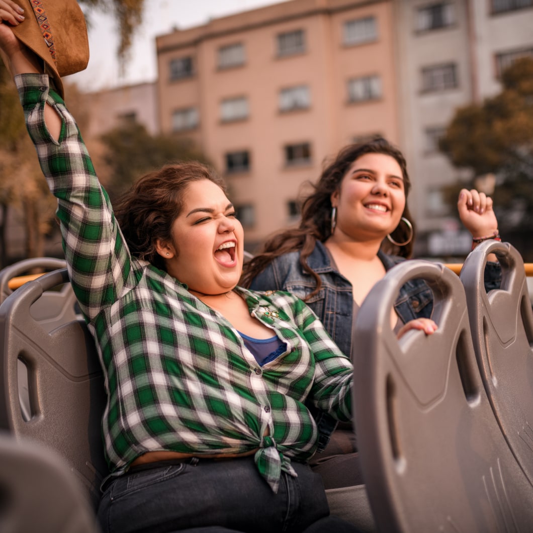 Two happy travellers riding on the top of a double-decker bus