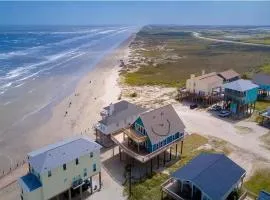 Martinis & Bikinis, a beach front house with toes in the sand drink in the hand.