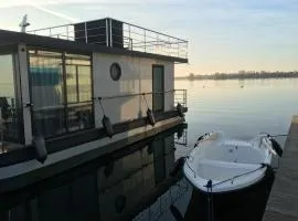Modernes festliegendes Hausboot mit großzügiger Dachterrasse und Ruderboot