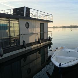 Modernes festliegendes Hausboot mit großzügiger Dachterrasse und Ruderboot, hotel di Röbel