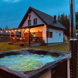 Domek z kominkiem nad jeziorem z jacuzzi ogrodowym