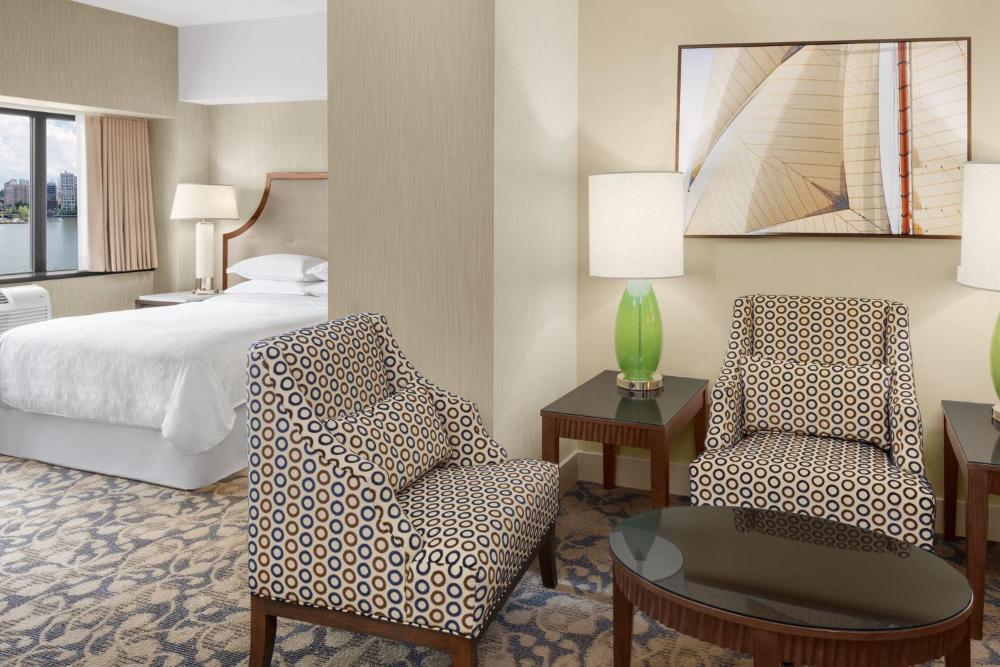 Guest room with a bed, patterned armchairs, and a coffee table at Sheraton Lincoln Harbor Hotel