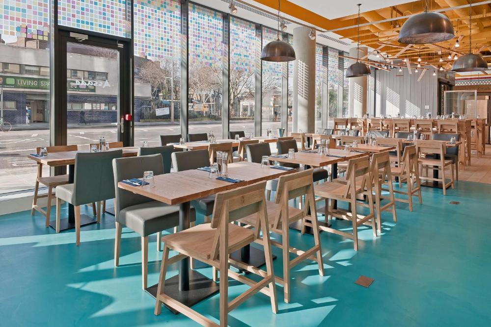 Dining space with wooden tables and chairs at Hampton by Hilton London Waterloo