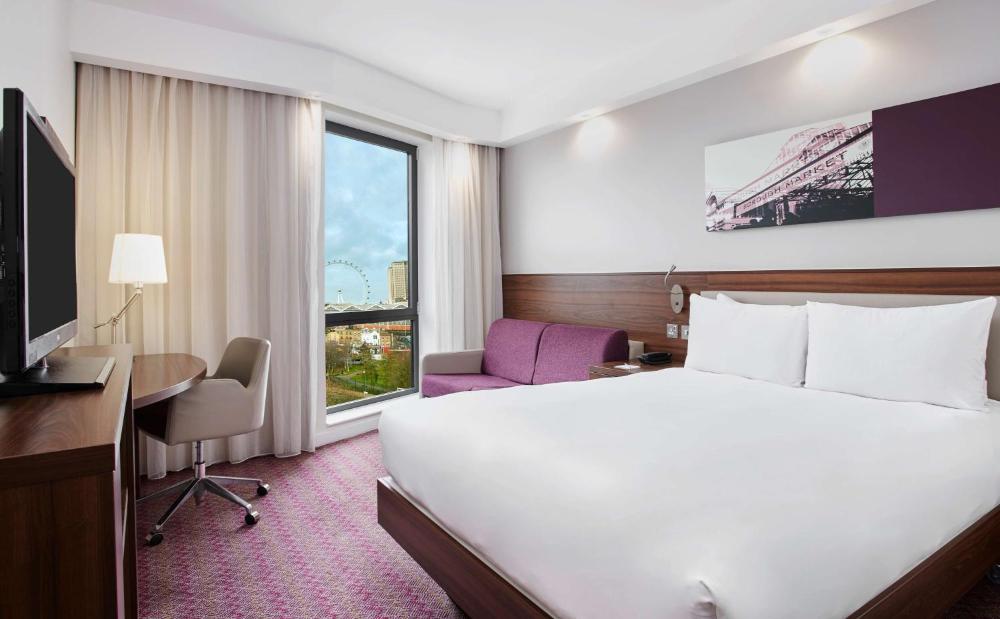 Guest room with a bed, desk, chair, and sofa at Hampton by Hilton London Waterloo
