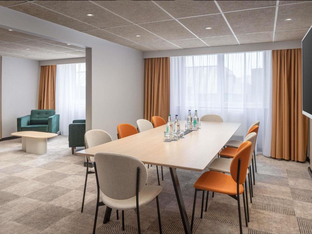 Meeting room with a long table, chairs, and lounge seating at ibis London Earls Court