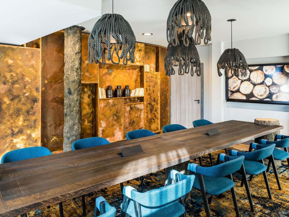 Conference room with a long table and blue chairs at Novotel London Canary Wharf
