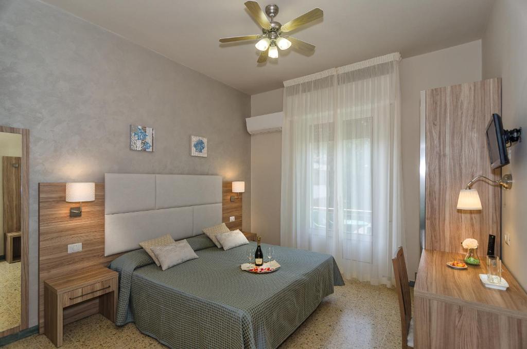 une chambre avec un lit et un ventilateur de plafond dans l'établissement Hotel Giardino, à Lido di Camaiore