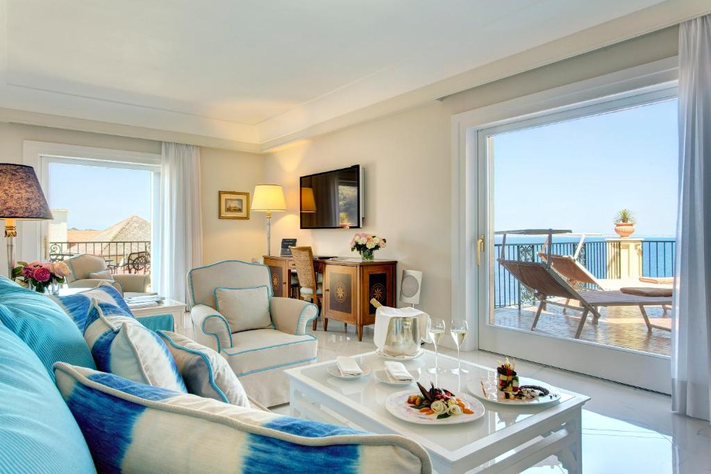 un salon avec un canapé bleu et une grande fenêtre dans l'établissement Grand Hotel Royal, à Sorrente