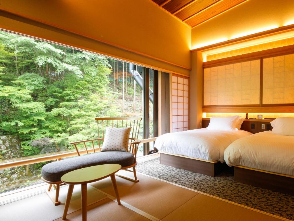 une chambre avec deux lits et une grande fenêtre dans l'établissement Asan Kotonami, à Manno