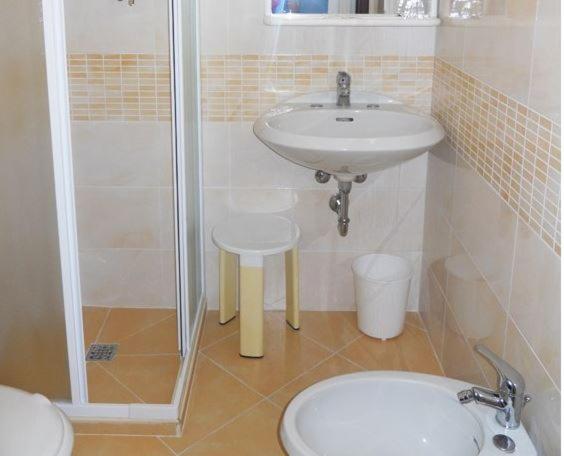 une salle de bain avec un lavabo, une douche et des toilettes dans l'établissement Hotel Daria, à Rimini