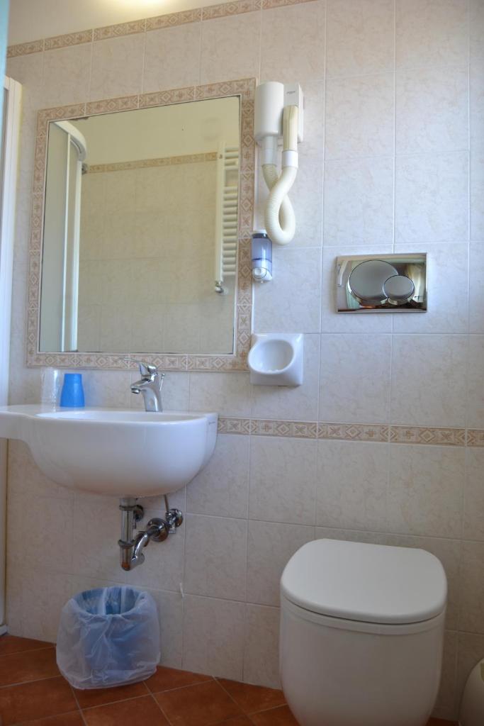 une salle de bain avec un lavabo, des toilettes et un miroir dans l'établissement Hotel Apis, à Rimini