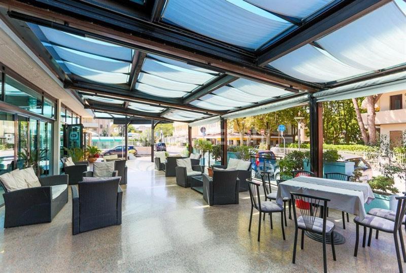 un restaurant avec des tables, des chaises et des fenêtres dans l'établissement Hotel Mirage, à Lido di Classe