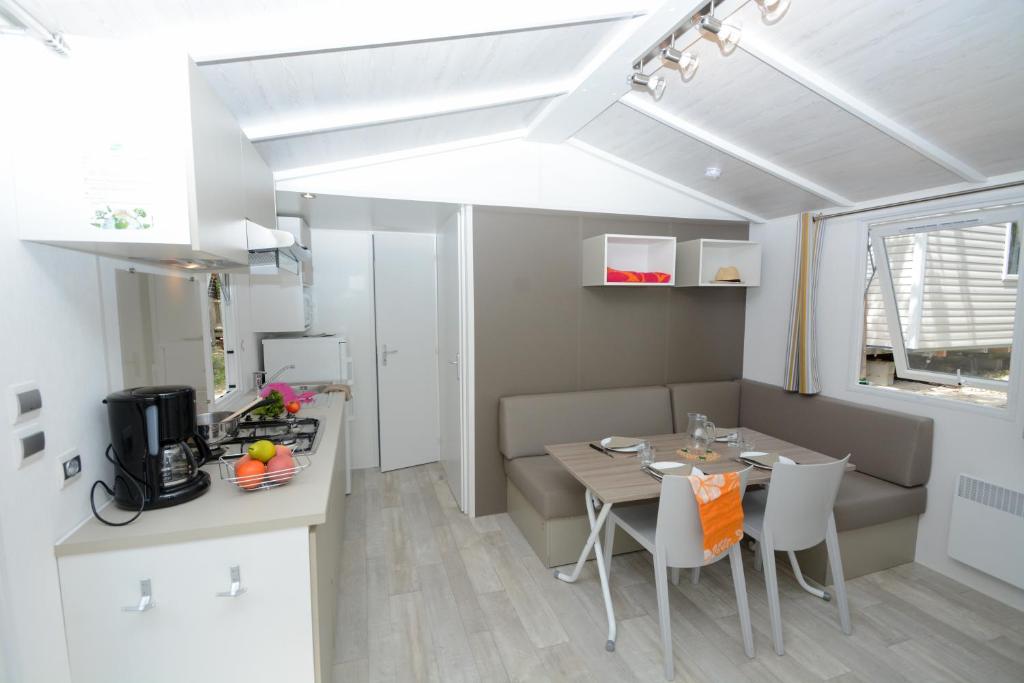 une salle à manger et une cuisine avec une table et des chaises dans l'établissement Camping Le Parc, à Saint-Paul-en-Forêt