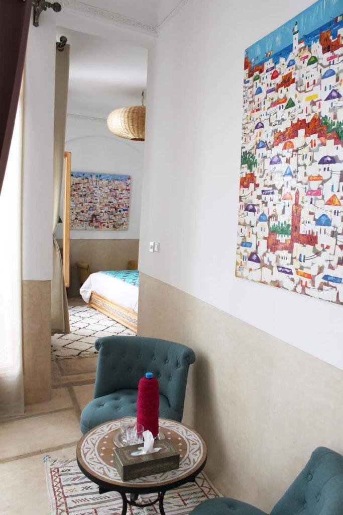 un salon avec une chaise bleue et une table dans l'établissement Jennat El Mossafir-Riad privé avec services, à Essaouira