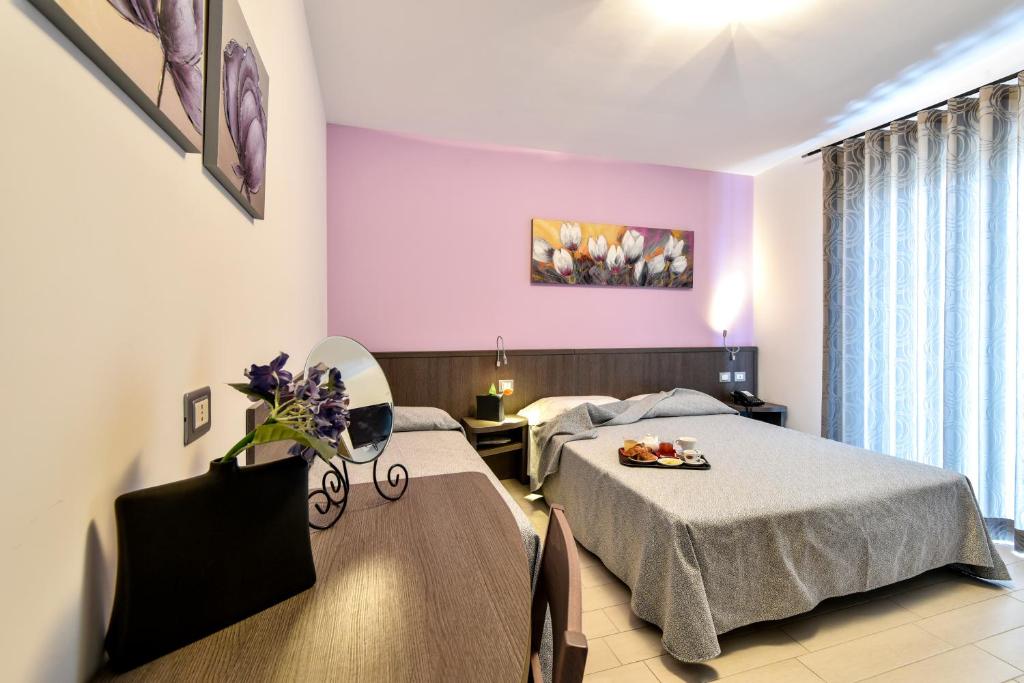 deux lits dans une chambre aux murs roses dans l'établissement Hotel Villa Bianca, à San Salvo