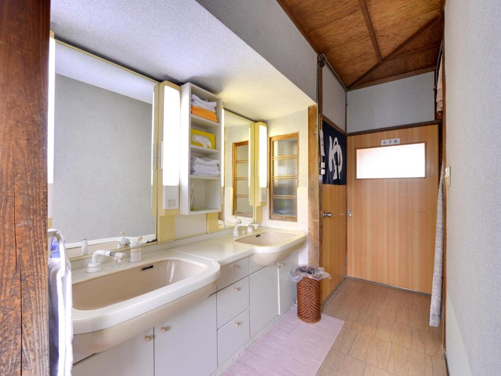 La salle de bains est pourvue de 2 lavabos, d'une baignoire et de miroirs. dans l'établissement Kikuya Ryokan, à Tonosho
