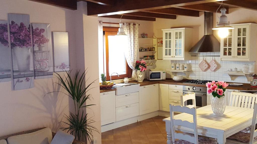 - une cuisine avec des placards blancs et une table fleurie dans l'établissement Villa Rosi, à Capitana