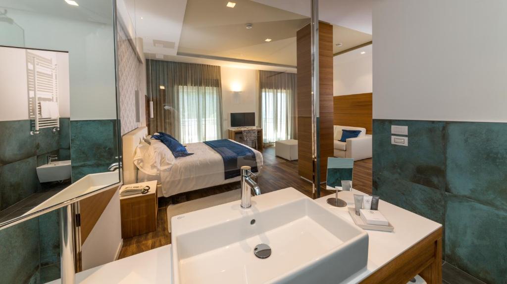 une salle de bain avec un lavabo et une chambre avec un lit dans l'établissement Hotel Aurora, à Lido di Jesolo
