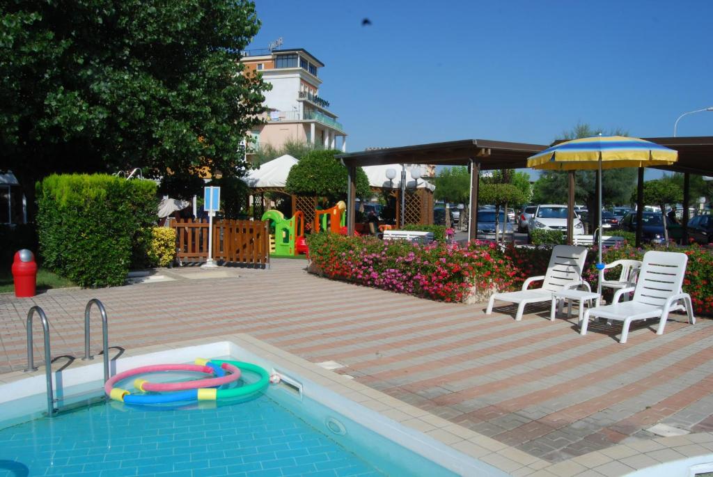 une piscine avec deux chaises et un parasol dans l'établissement Hotel Perla, à Senigallia 24 autres photos