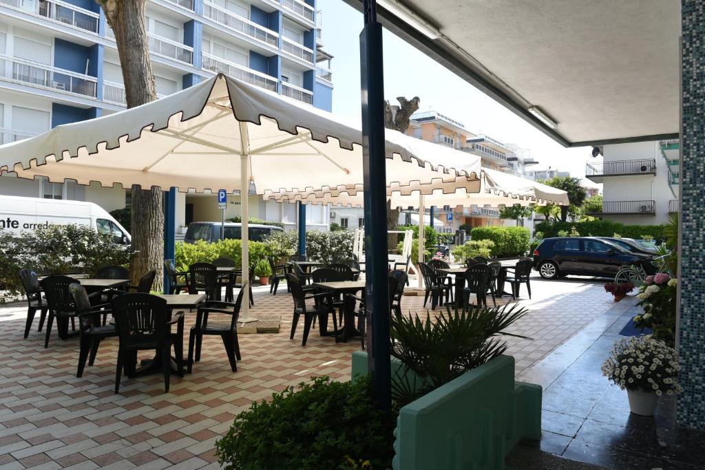 un patio extérieur avec tables, chaises et parasols dans l'établissement Hotel Savoia, à Lido di Jesolo