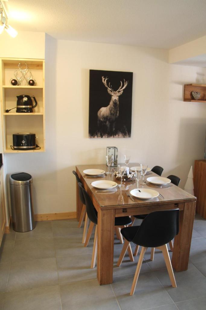 une salle à manger avec une table en bois et un tableau de cerf dans l'établissement Résidence : Le Crystal Chalet, à Les Deux Alpes