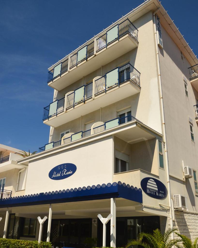 un grand bâtiment blanc avec une enseigne dessus dans l'établissement Hotel Karin, à Rimini