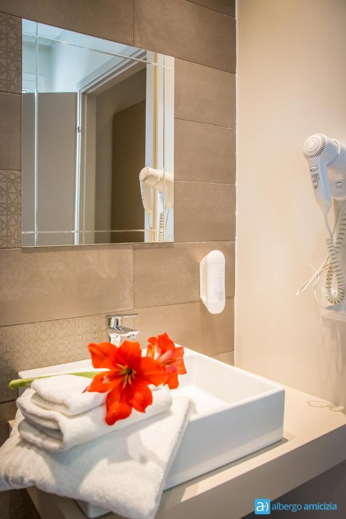- un lavabo avec des serviettes et une fleur dans l'établissement Hotel Amicizia, à Rimini 139 autres photos