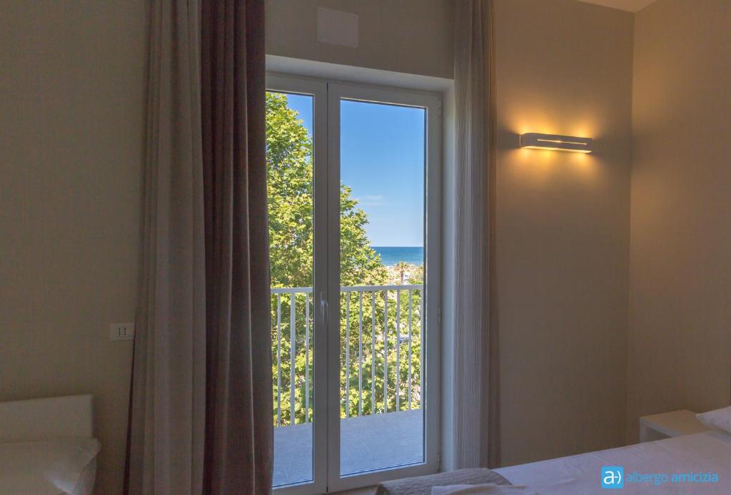 une chambre avec une fenêtre avec vue sur l'océan dans l'établissement Hotel Amicizia, à Rimini