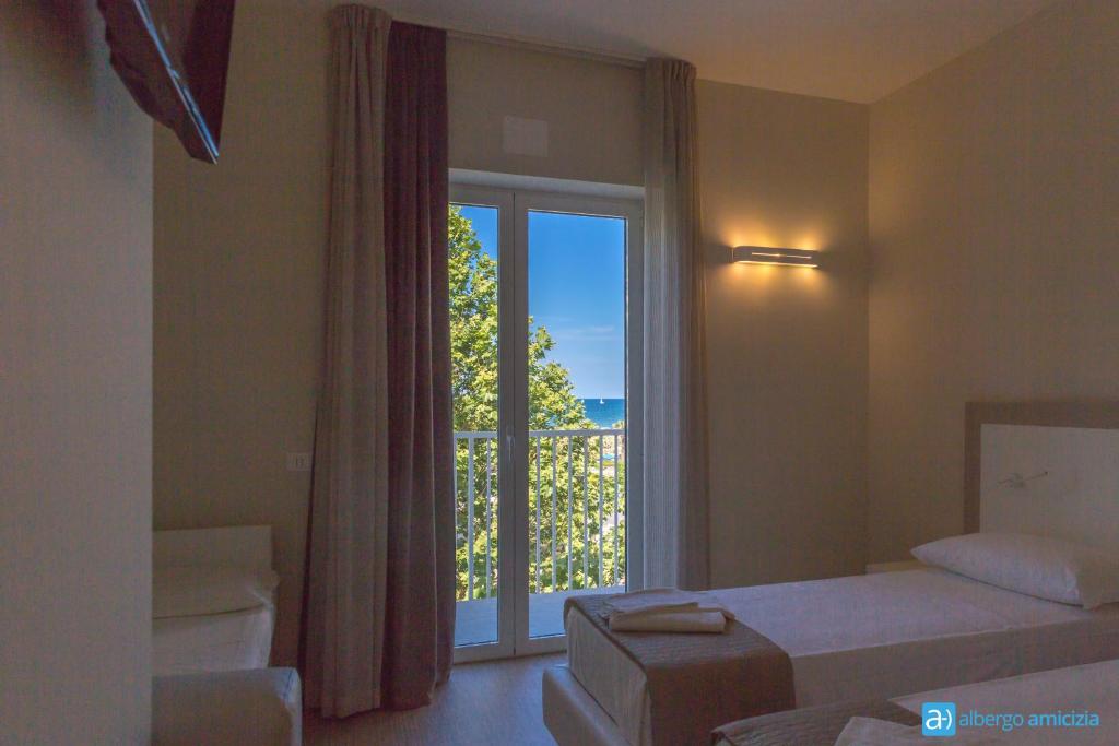 une chambre avec un lit et une grande fenêtre dans l'établissement Hotel Amicizia, à Rimini