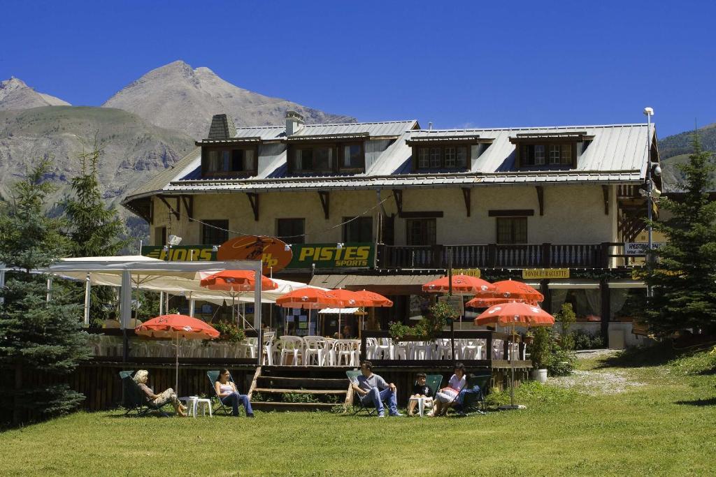 un groupe de personnes assises sous des parasols devant un bâtiment dans l'établissement Hotel Franz, à Allos