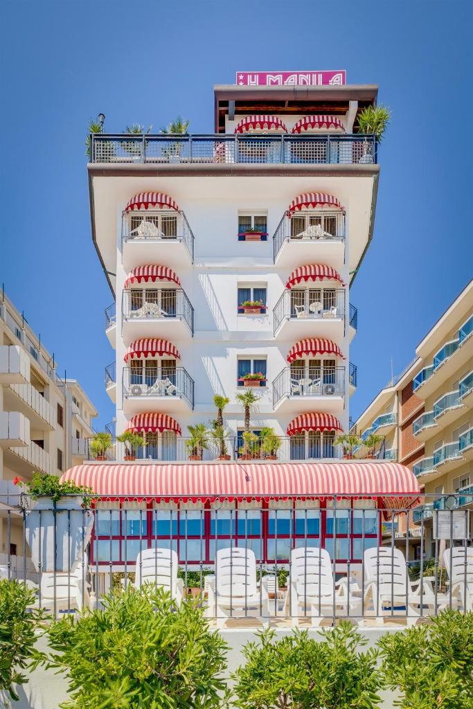 un grand bâtiment blanc avec des chaises devant dans l'établissement Hotel Manila, à Lido di Jesolo