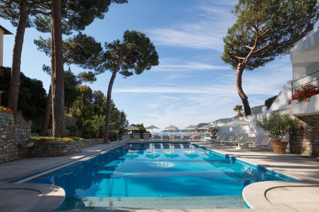 une piscine avec de l'eau bleue et des arbres dans l'établissement Imperiale Palace Hotel, à Santa Margherita Ligure