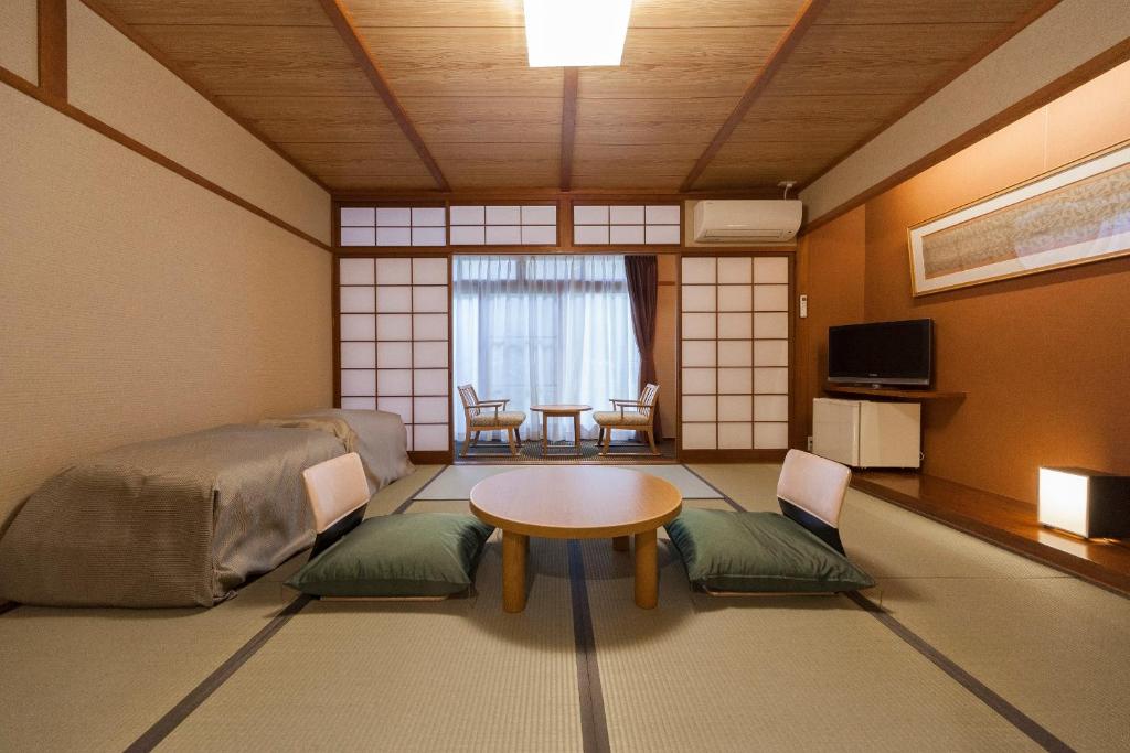 une pièce avec une table et des chaises dans une pièce dans l'établissement Onsen Guest House Aobato no Su, à Matsue