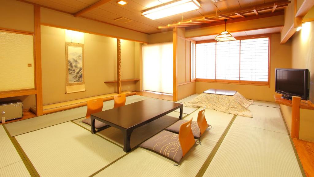 un salon avec une table, des chaises et une télévision dans l'établissement Isawa View Hotel, à Fuefuki
