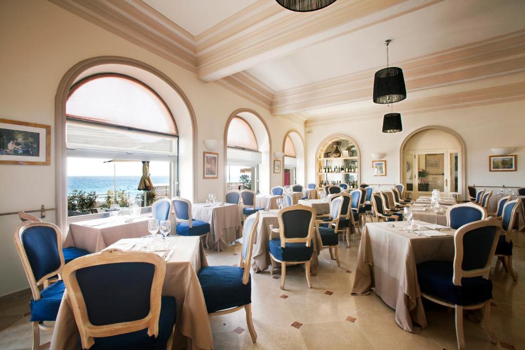 une salle à manger avec tables, chaises et fenêtres dans l'établissement Hotel Parigi & Spa, à Bordighera