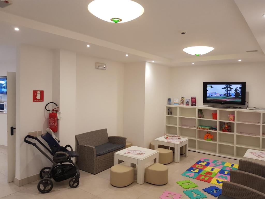 - un salon avec une poussette et une télévision dans l'établissement Hotel Helvetia, à Lignano Sabbiadoro