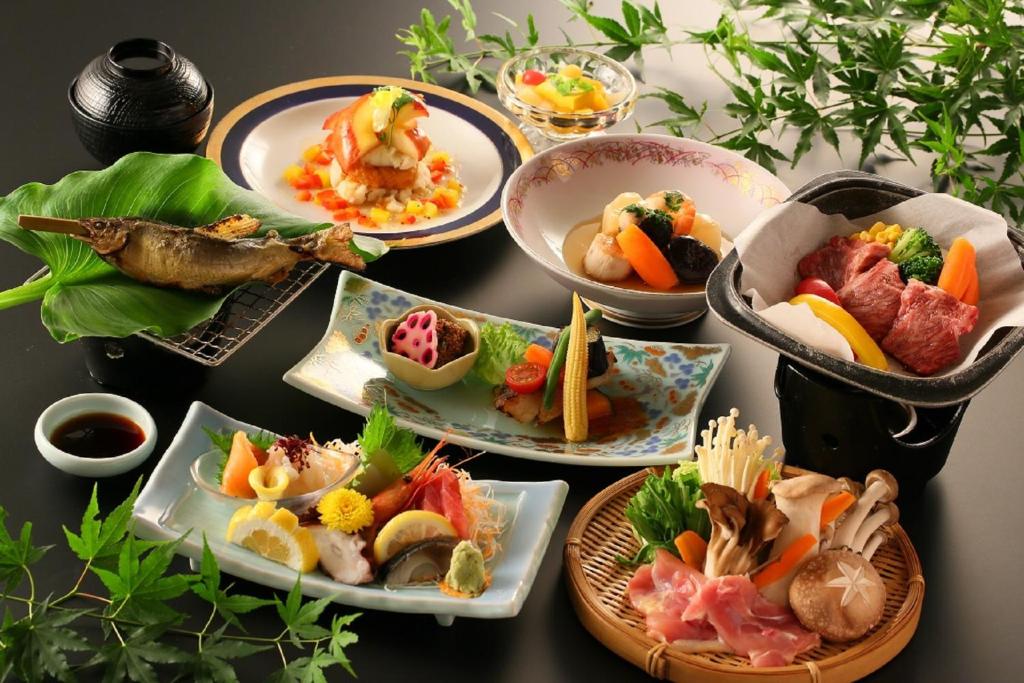 une table avec de nombreuses assiettes de nourriture dessus dans l'établissement Hotel Housei, à Yamanouchi 27 autres photos