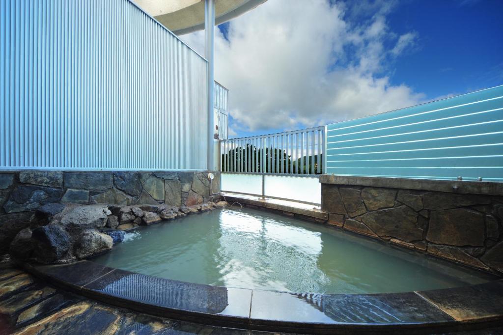 une piscine d'eau avec une clôture et un bâtiment dans l'établissement Harunako Onsen Yusuge, à Takasaki