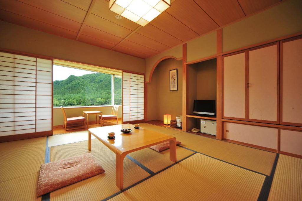 un salon avec une table et une grande fenêtre dans l'établissement Harunako Onsen Yusuge, à Takasaki