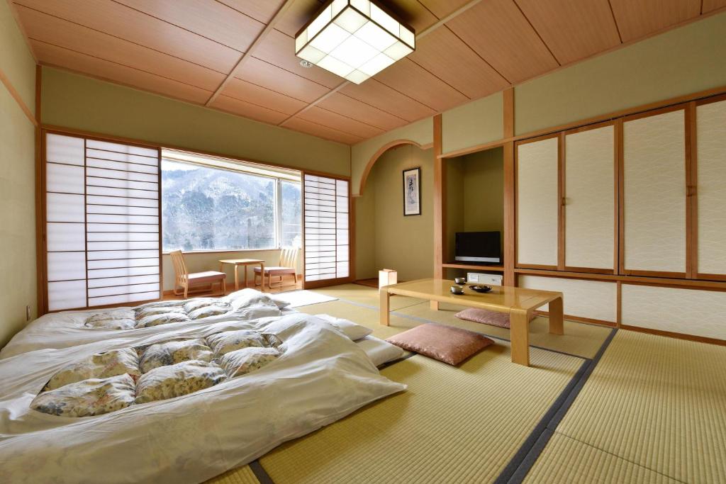 un grand lit dans une chambre avec une grande fenêtre dans l'établissement Harunako Onsen Yusuge, à Takasaki