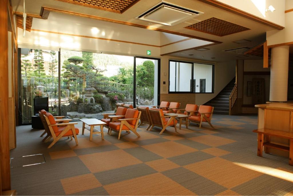 un restaurant avec des tables et des chaises orange et une grande fenêtre dans l'établissement Nezame Hotel, à Agematsu