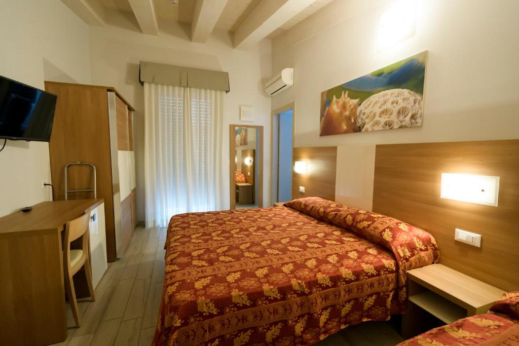 une chambre d'hôtel avec un lit et une télévision dans l'établissement Mondial, à Cervia