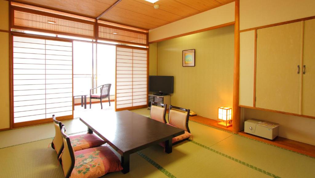une salle à manger avec une table, des chaises et une télévision dans l'établissement Hotel Hana Isawa, à Fuefuki