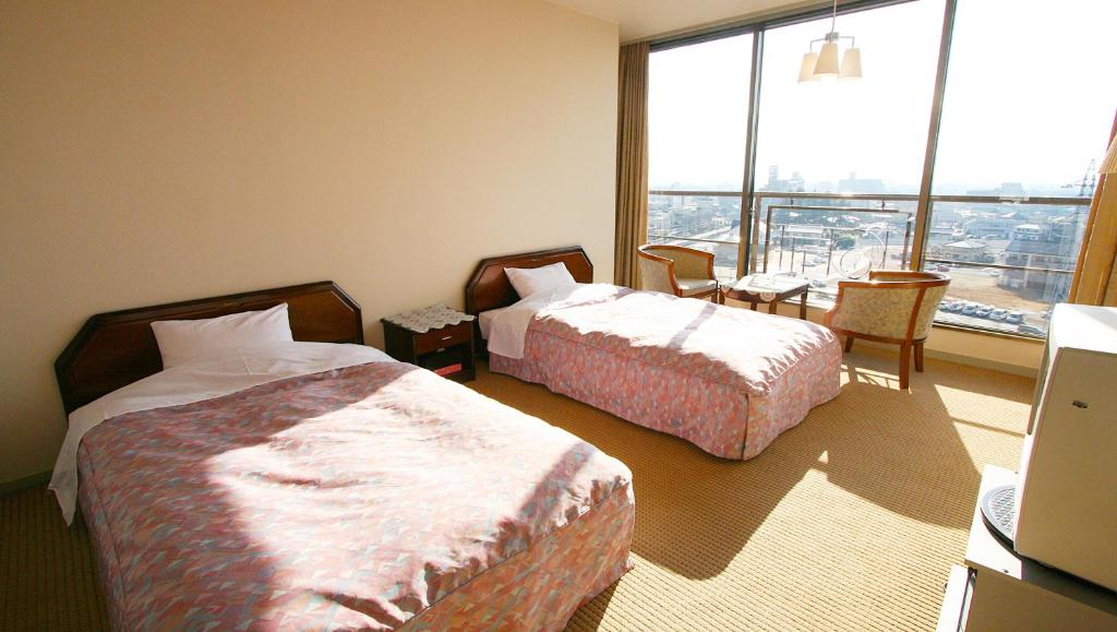une chambre d'hôtel avec deux lits et une grande fenêtre dans l'établissement Hotel Hana Isawa, à Fuefuki