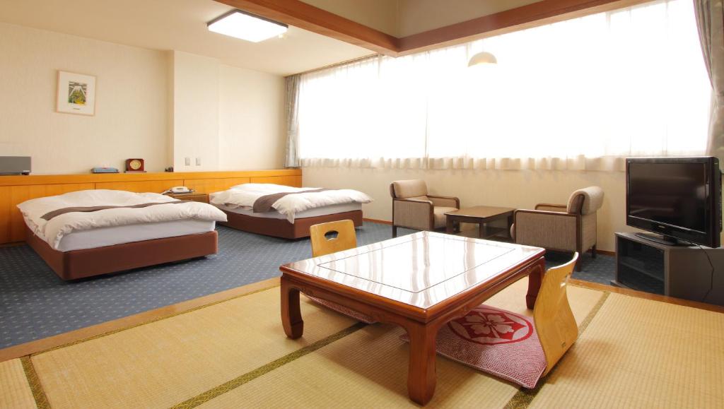 Cette chambre comprend 2 lits, une table et une télévision. dans l'établissement Kasugai View Hotel, à Fuefuki 37 autres photos