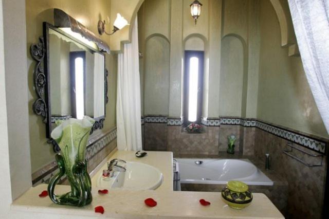 La salle de bains est pourvue d'un lavabo, d'une baignoire et d'un vase fleuri. dans l'établissement Villa Riadana, à Agadir