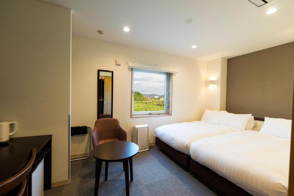 une chambre d'hôtel avec deux lits, un bureau et une fenêtre dans l'établissement Mikasa Tennen Onsen Taikonoyu Sparesort Hotel Taiko Bettei Hatago, à Iwamizawa
