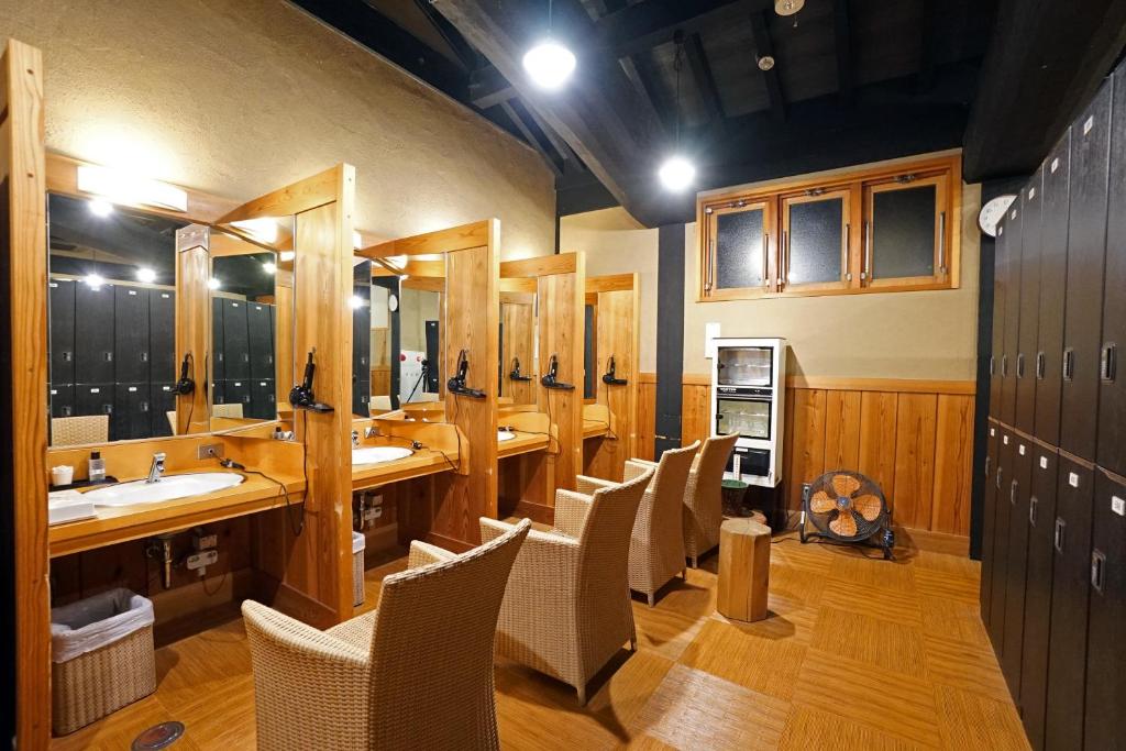 La grande salle de bains est pourvue d'une rangée de lavabos et de chaises. dans l'établissement Mikasa Tennen Onsen Taikonoyu Sparesort Hotel Taiko Bettei Hatago, à Iwamizawa