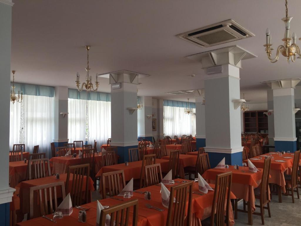 une salle à manger avec des tables et des chaises orange dans l'établissement Hotel Consuelo, à Lignano Sabbiadoro